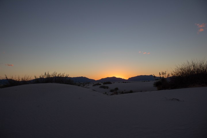 The sun setting behind the mountains at White Sands National Monument.