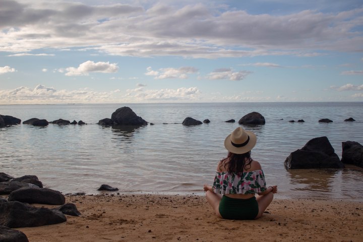 Finding a moment of peace while meditating to the sound of the gentle waves in Hawaii.